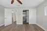 Room featuring wood-finish flooring, a ceiling fan with integrated lighting, and a reach-in closet with built-in shelving