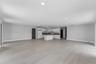Open-concept interior featuring light wood-finish flooring, recessed lighting, and a kitchen equipped with white cabinetry, a center island, and dark-