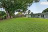 Expansive backyard featuring a large mature tree, a covered patio, and wood-paneled privacy fencing