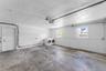 Garage space featuring concrete flooring, painted block walls, two windows, and an exterior access door
