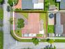 Corner lot featuring a multi-faceted roofline, paved driveway, concrete patio, and fenced perimeter