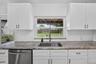 Kitchen featuring white shaker-style cabinetry, stone-patterned countertops, a stainless steel undermount sink with a gooseneck faucet, white subway t