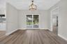 Dining area featuring wood-finish flooring, a geometric pendant light fixture, and sliding glass doors