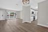 Open interior featuring wood-finish flooring, white cabinetry, integrated stainless steel appliances, a picture window, and a geometric pendant light 