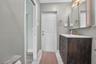 Bathroom vanity with dark wood-finish cabinetry, a stone-surface countertop, and gold-tone fixtures, complemented by decorative patterned floor tile a