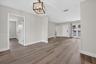 Interior space featuring wood-finish flooring, neutral wall paint, a geometric open-frame chandelier, and multi-lite exterior glass doors