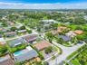 Aerial perspective of a corner lot featuring a tile roof, paved driveway, enclosed yard, and swimming pool