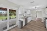 Kitchen featuring white cabinetry, stone-surface countertops, subway tile backsplash, stainless steel appliances, and sliding glass doors to a covered