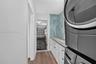 Utility room featuring white shaker-style cabinetry, stone-finish countertops, blue vertical tile backsplash, and wood-finish flooring