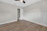 Room featuring wood-finish flooring, white board-and-batten wall detailing, and a ceiling-mounted light fixture with fan