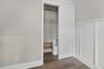 Closet with white sliding door, adjustable wire shelving, and wood-finish flooring, complemented by wall-mounted wainscoting