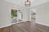Wood-finish flooring, geometric-frame pendant lighting, and sliding glass doors with access to a covered patio