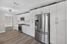 Kitchen featuring white shaker-style cabinetry, stainless steel appliances, stone-finish countertops, subway tile backsplash, and wood-finish flooring