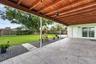 Covered patio featuring a wood-beam ceiling, tile flooring, and a large backyard with a privacy fence