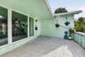 Covered entryway featuring large-format stone-tile flooring, expansive picture windows, and decorative concrete screen block accents