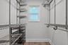 Storage space featuring wall-mounted wire shelving, hanging rods, and wood-finish flooring with a single window