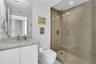 White vanity with a light-toned countertop, rectangular undermount sink, and a frameless mirror