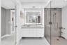 Modern bathroom featuring a floating vanity with integrated sink, illuminated mirror, and a glass-enclosed shower with a rain showerhead