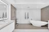 Modern bathroom with a freestanding soaking tub, glass-enclosed shower, wood-finish flooring, and a vanity with an illuminated mirror