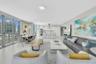 Open-concept living space with expansive sliding glass doors, white flooring, recessed lighting, and a modern kitchen with built-in appliances