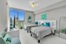 Expansive window with city background, overhead ceiling light fixture, white headboards, and light-toned flooring