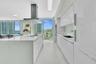 Sleek kitchen featuring an oversized island, integrated cooktop, stainless steel range hood, wall ovens, and custom white cabinetry