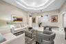 Living area featuring a multi-tiered tray ceiling, polished tile flooring, recessed lighting, and double-entry doors with a transom window