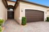 Stucco exterior featuring an arched entryway, double-panel front doors with a fanlight window, a multi-car garage with a raised-panel door, and a deco