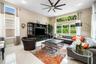 High-ceiling living area featuring large windows, neutral-toned tile flooring, recessed lighting, and a multi-blade ceiling fan