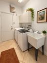 Laundry area featuring tile flooring, white built-in wall cabinetry, and a deep basin utility sink with a dual-handle faucet
