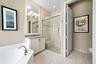 Bathroom featuring a walk-in shower with a glass enclosure and built-in bench, a soaking tub, a vanity with stone-finish countertop, and tiled floorin