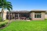Exterior featuring a stucco facade, a screened-in lanai with paver flooring, a tile roof, and a landscaped lawn