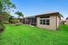 Stucco exterior featuring a screened-in lanai, multi-pane windows, a tiled roof, and a manicured lawn