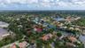 Aerial perspective of a residential property situated in a suburban community, featuring mature tropical landscaping and proximity to a winding waterw