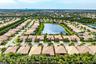Aerial perspective of a residential community centered around a large lake, featuring multiple tile-roof homes, paved street infrastructure, and estab