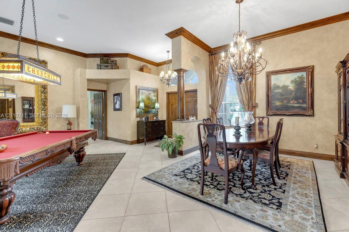 Elegant entertainment spaces featuring a crystal chandelier, formal dining area with wood-finish flooring, and a billiards room with traditional styli