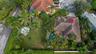 Aerial perspective of a property featuring a tile roof, an in-ground swimming pool, extensive landscaping with mature palm trees, and a perimeter fenc