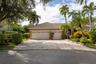 Exterior featuring a two-car garage, tiled roof, paved driveway, and mature landscaping
