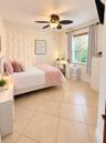 Large-format ceramic tile flooring, ceiling fan with integrated light fixture, window with horizontal blinds, and neutral-toned wall paint