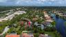 Aerial perspective of a residential property featuring a tiled roof, mature landscaping, palm trees, and a spacious lot