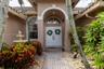 Covered entryway featuring a stone-paver walkway, arched portico, double-door entry with a semi-circular transom window, and an integrated stone fount