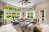 High-ceilinged living area featuring expansive windows with transom glass, large-format tile flooring, and a ceiling fan