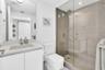 Modern bathroom featuring a frameless glass shower enclosure, a full-height vanity mirror, a single-sink vanity with white cabinetry, and a walk-in sh