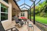 Screened-in lanai featuring stone paver flooring, vaulted ceiling, built-in ceiling fan, and access to a landscaped backyard