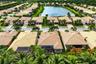 Aerial perspective of a residential community featuring tile roofs, paved roadways, palm tree landscaping, and a central water feature