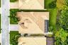 Aerial view featuring a multi-gabled tile roof, a screened-in enclosure, concrete driveway, and landscaped perimeter