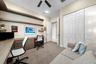 Built-in desk with integrated drawer storage, custom floating shelves, ceiling fan, and floor-to-ceiling bi-fold closet doors