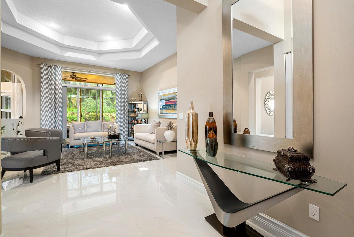 Polished tile flooring, tray ceilings with recessed lighting, and large glass sliding doors providing natural light