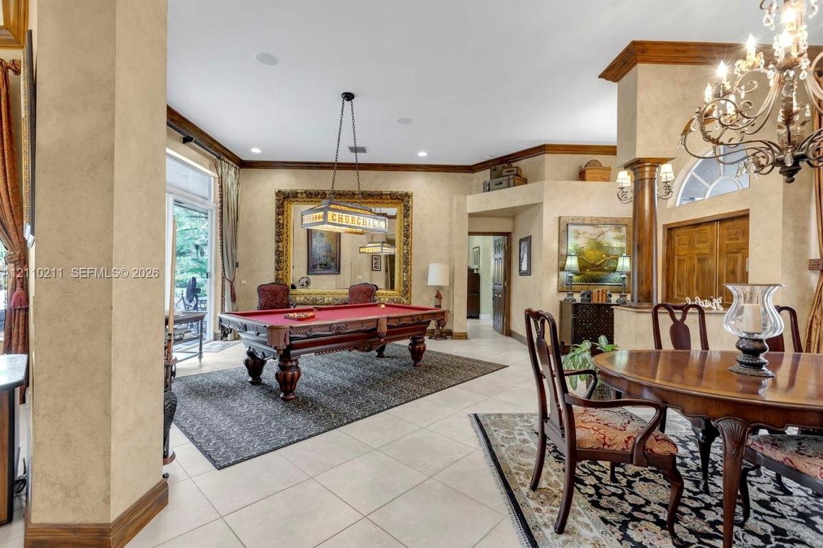 Expansive living area featuring custom crown molding, textured wall finishes, arched architectural detailing, a decorative wood column, and an ornate 