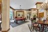 Expansive living area featuring custom crown molding, textured wall finishes, arched architectural detailing, a decorative wood column, and an ornate 